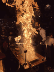 a man wearing a mask stands in front of a fire with a sign that says ' flammable ' on it