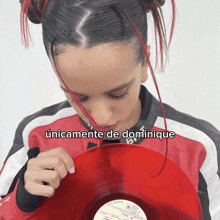 a woman in a red jacket is holding a red record with the words únicamente de dominique below her