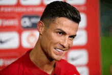 a close up of a man in a red shirt smiling