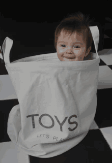 a little boy is sitting in a white bag that says toys on it