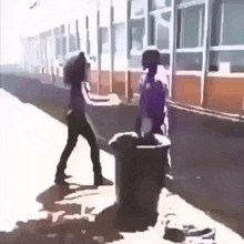 a man and a woman are standing next to each other on a sidewalk next to a trash can .