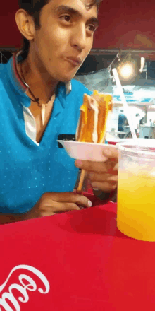 a man sitting at a table with a cup of orange juice and a plate of food