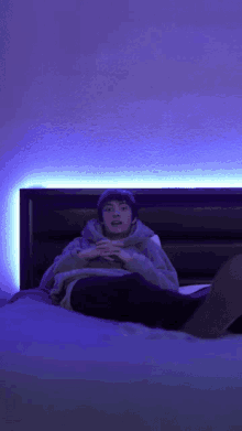 a young man is laying on a bed under a blue light