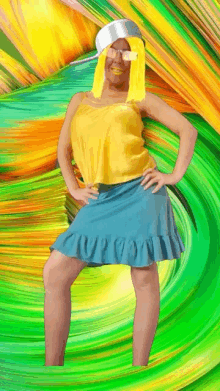 a woman in a yellow top and blue skirt is standing with her hands on her hips in front of a colorful background