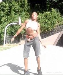 a man in a crop top and shorts is dancing in front of a basketball court .