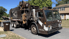 a garbage truck that says wd on the side is parked in front of a house