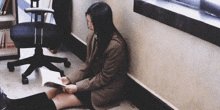 a girl sits on the floor reading a book