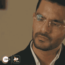 a close up of a man wearing glasses and a logo for zee 5