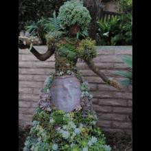 a statue of a woman made out of plants and branches