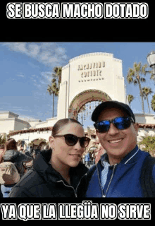 a man and a woman are posing for a picture in front of a sign that says hollywood studios .