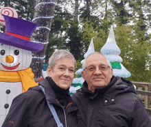 a man and woman pose in front of a snowman