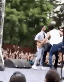 a man in a white shirt is playing a guitar on a stage in front of a crowd of people