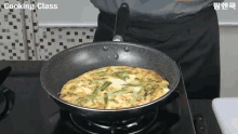 a person is cooking an omelet in a frying pan on a stove with cooking class written on the bottom