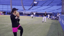 a woman is throwing a baseball in an empty stadium with a sign that says ' toyota ' on it