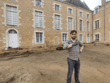 a man wearing black gloves stands in front of a large stone building