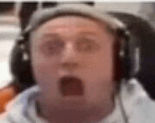 a close up of a man wearing headphones and making a surprised face .