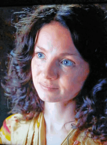 a close up of a woman 's face with curly hair