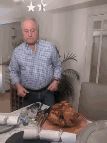 a man in a plaid shirt is standing in front of a cutting board with a large piece of meat on it