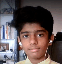 a young boy wearing headphones and a yellow shirt looks at the camera .