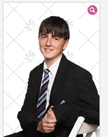 a young man in a suit and tie is sitting on a chair