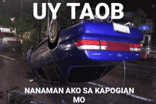 a blue car is upside down with the words uy taob written above it