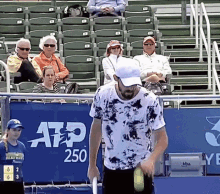 a man in a tie dye shirt is holding a tennis racquet in front of a banner that says atp 250