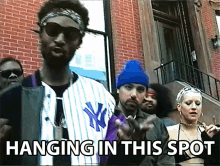 a group of people are standing in front of a brick building with the words " hanging in this spot " on the bottom