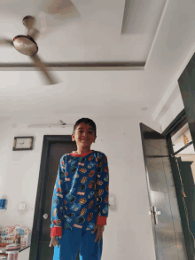 a young boy wearing a marvel shirt stands in front of a door