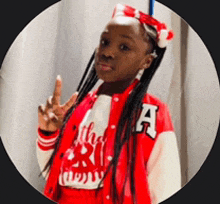 a young girl wearing a red jacket with the letter a on it giving a peace sign