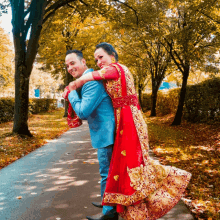 a man is carrying a woman in a red and gold dress