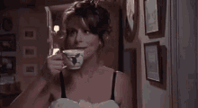 a woman in a bra is drinking from a cup in a room .