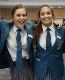 two young girls in school uniforms and ties are posing for a picture .