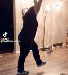 a woman is dancing in a living room with a tiktok laughitupmoments watermark