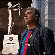 a man standing next to a lionel messi statue