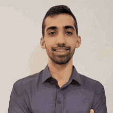 a young man with braces on his teeth is smiling for the camera while standing with his arms crossed .