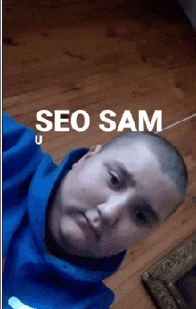 a man with a shaved head is taking a selfie with the words seo sam written on the bottom .