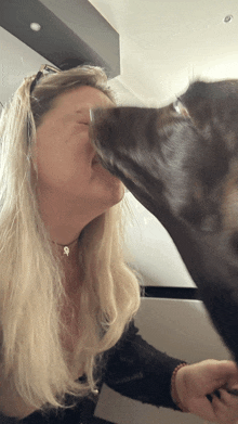 a woman is being kissed by a dog that is licking her face