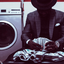 a man in a suit is holding a stack of money in front of a washer