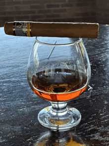 a cohiba cigar is resting on top of a glass of cognac