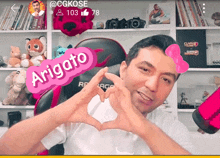 a man making a heart with his hands with a sticker that says " arigato "