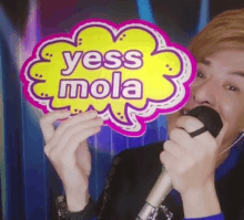 a man singing into a microphone while holding a speech bubble that says yess mola