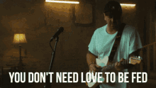 a man playing a guitar in front of a microphone with the words " you don t need love to be fed "