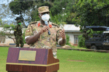 a man wearing a mask stands at a podium in front of a police car