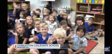 a group of children are sitting on the floor in front of a sign that says " charleston collegiate school "