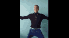 a man in a black turtleneck and blue pants is jumping in the air with his arms outstretched .