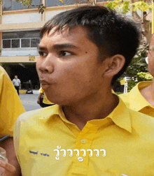 a young man wearing a yellow shirt with the word eee on the collar