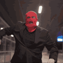 a man wearing a red mask and a black suit