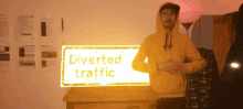 a man wearing a yellow hoodie stands in front of a sign that says diverted traffic