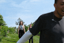 a man and two women are walking in a grassy area