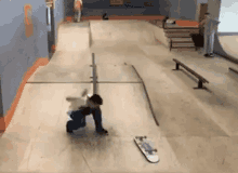 a young boy is falling off a skateboard in a skate park .